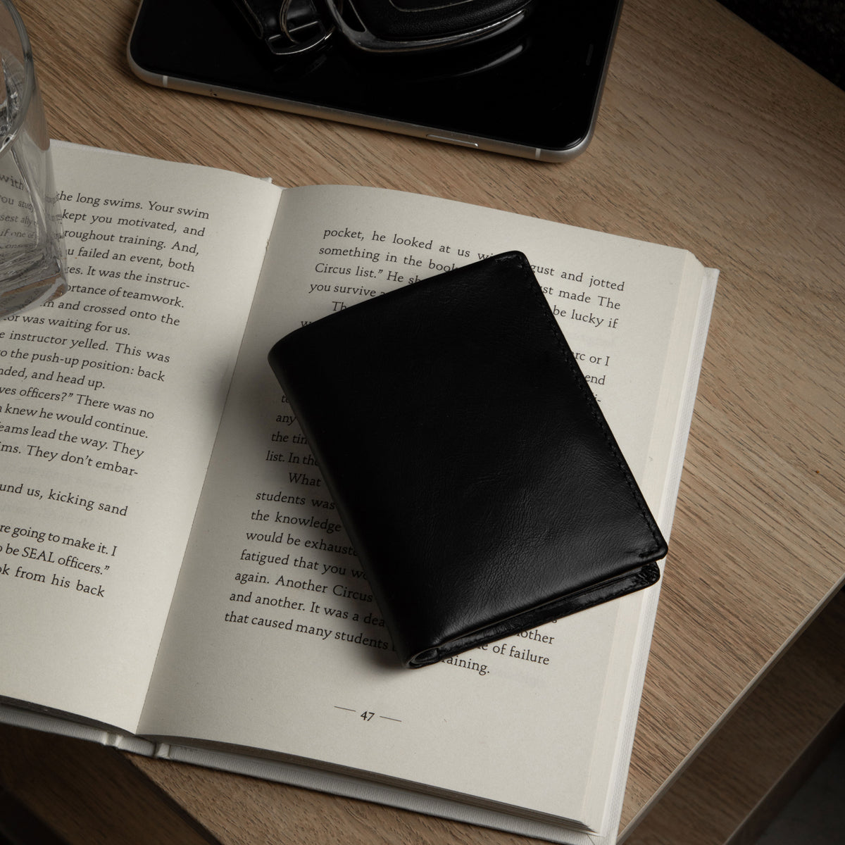 Black wallet on an open book with a smartphone in the background